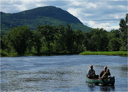 Two people in a canoe with Mt. Katahdin in the background.
