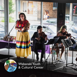 Three musicians play a drum and violins with the Wabanaki Youth & Cultural Center logo in the corner