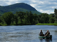 Two people in canoe on a lake with Katahdin in background